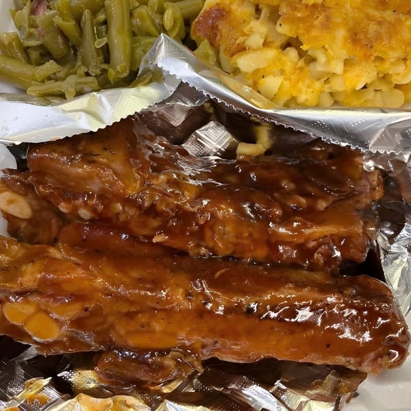 Gail's Soul Food ribs with barbecue sauce, green beans, and macaroni and cheese in a foil container.