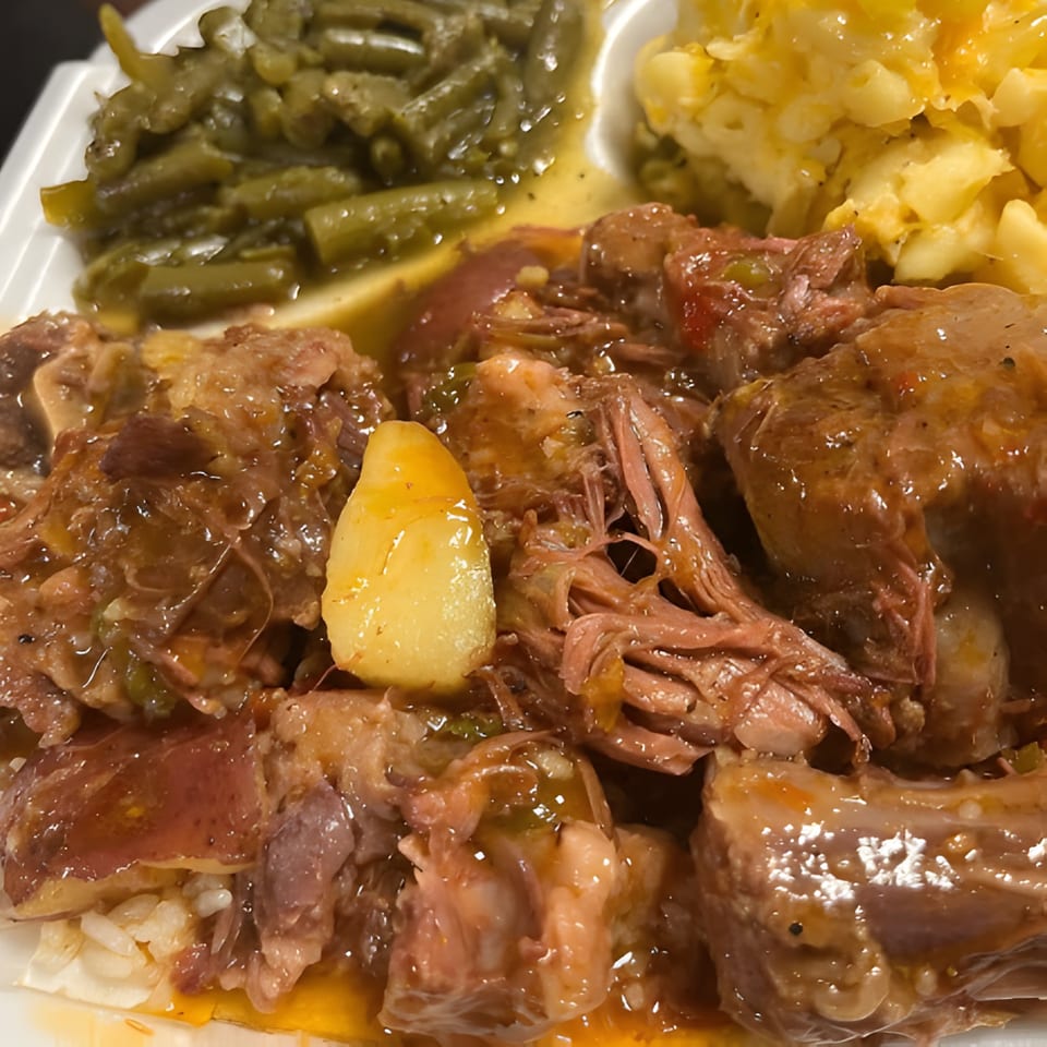 Close-up of Gail's Soul Food oxtails with gravy, green beans, and macaroni and cheese.
